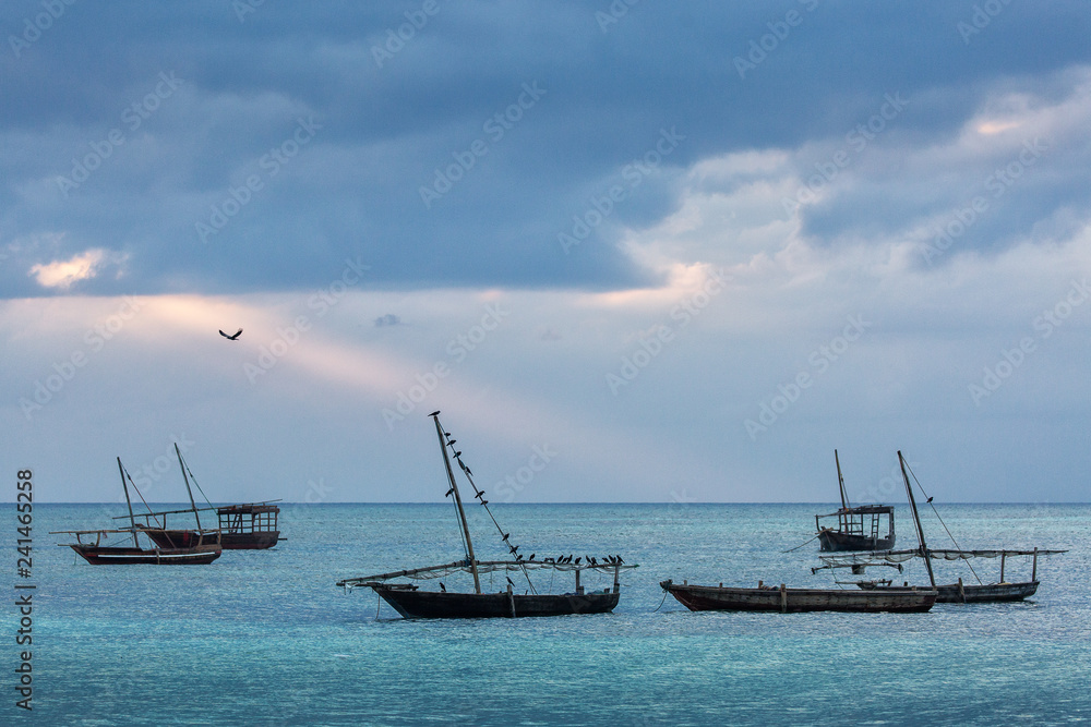 Fishing boats in ocean with birds and storm clouds in background. Zanzibar, Tanzania. Fishing boats in ocean with birds and storm clouds in background. Zanzibar, Tanzania.