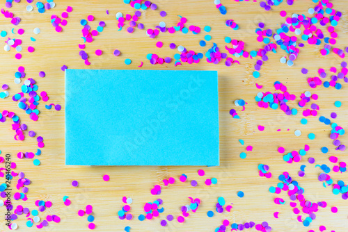 Festive party or carnival border of colorful confetti on a wood background and blue paper with blank copy space.