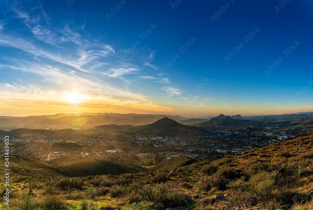 Bright Sun Setting Over City and Mountains