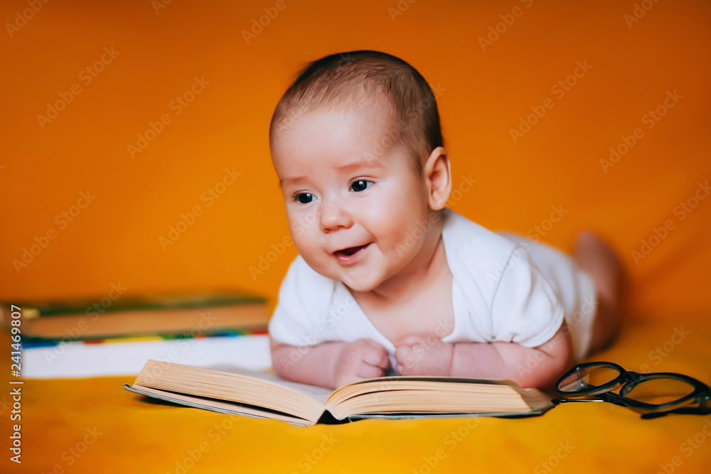 Adorable 3 months old baby looking and reading a book. Happy child playing and discovery. Early development, learning and education of kid Adorable 3 months old baby looking and reading a book. Happy child playing and discovery. Early development, learning and education of kid