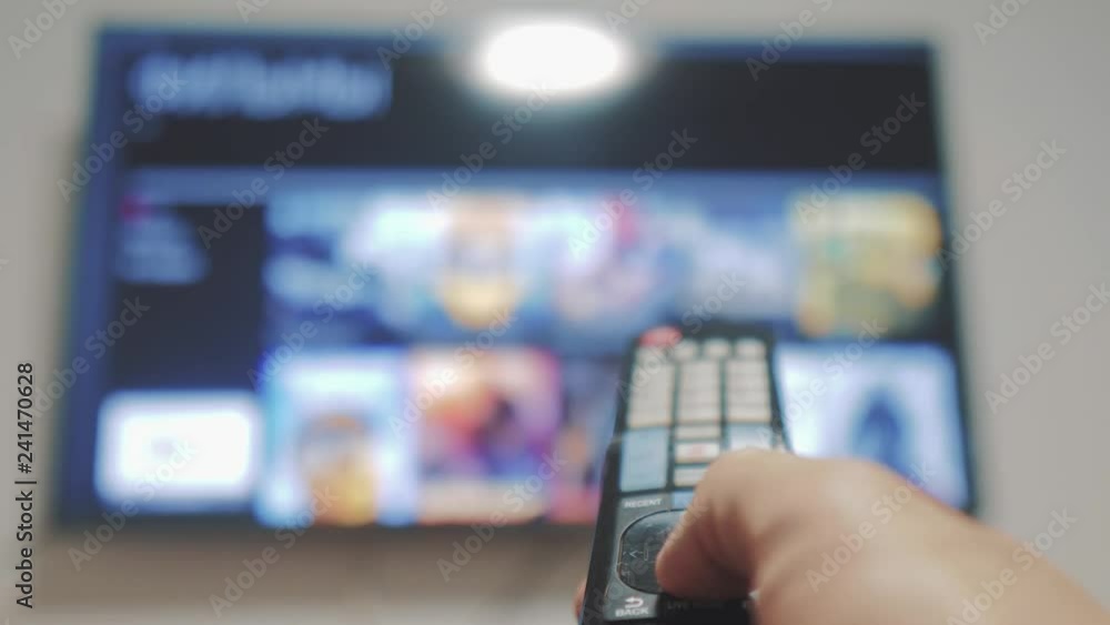 Smart tv with apps and hand. Male lifestyle hand holding the remote control turn off smart tv lifestyle . man hand controls TV holding remote. concept internet online cinema Smart tv with apps and hand. Male lifestyle hand holding the remote control turn off smart tv lifestyle . man hand controls TV holding remote. concept internet online cinema