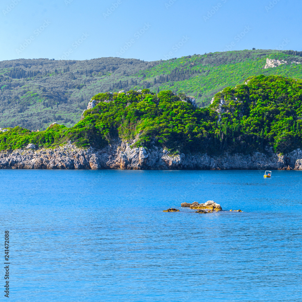 Beautiful summer panoramic seascape. View of the cliff into the sea bay with crystal clear azure water in sunshine daylight. Boats and yachts in the harbor. Mediterranean sea, somewhere in Europe.