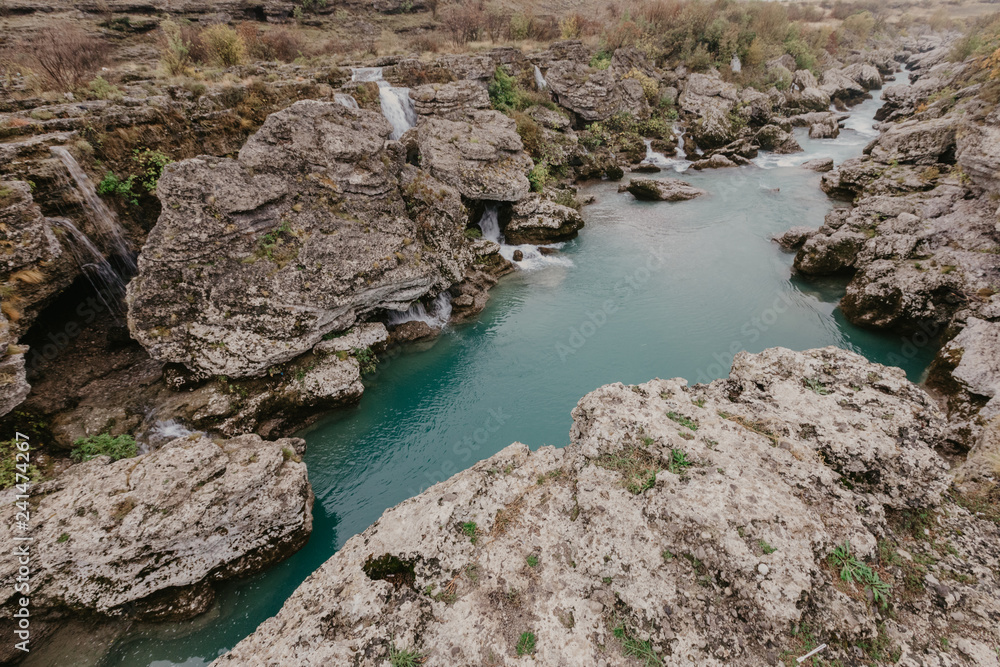 Mountain river with huge, big, and small stones and rocks on riverbed.