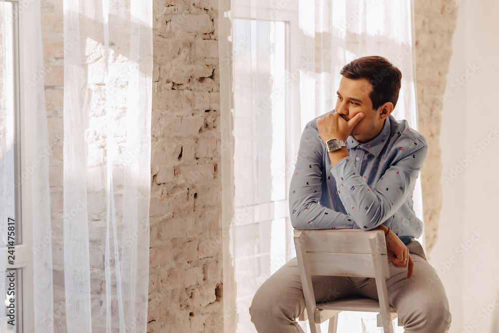 young stylish guy in light sunny interior in philosophy mood thinking