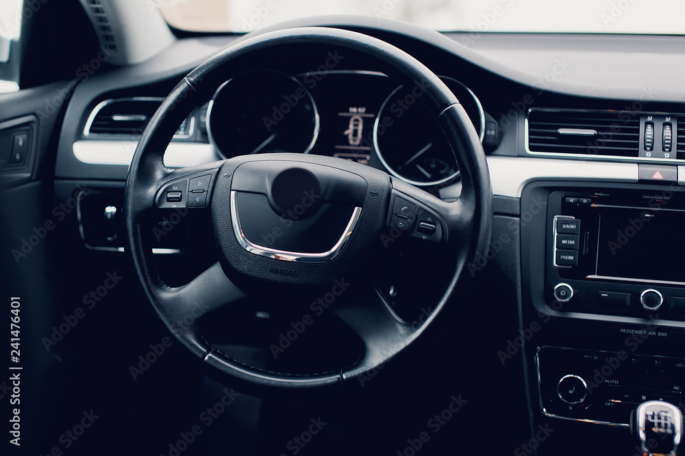 Steering wheel in a new car. Steering wheel with control buttons. Modern car interior in black color. Steering wheel in a new car. Steering wheel with control buttons. Modern car interior in black color.