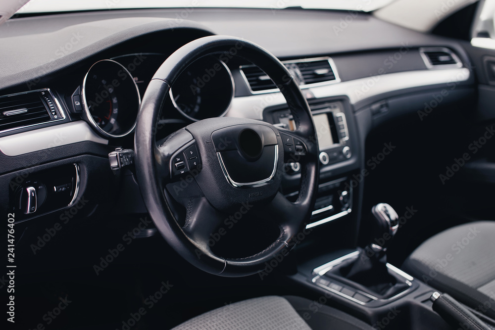 Steering wheel in a new car. Steering wheel with control buttons. Modern car interior in black color.