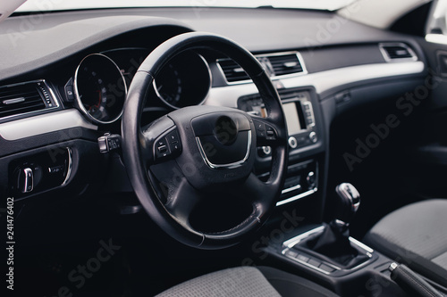 Steering wheel in a new car. Steering wheel with control buttons. Modern car interior in black color. © kucheruk