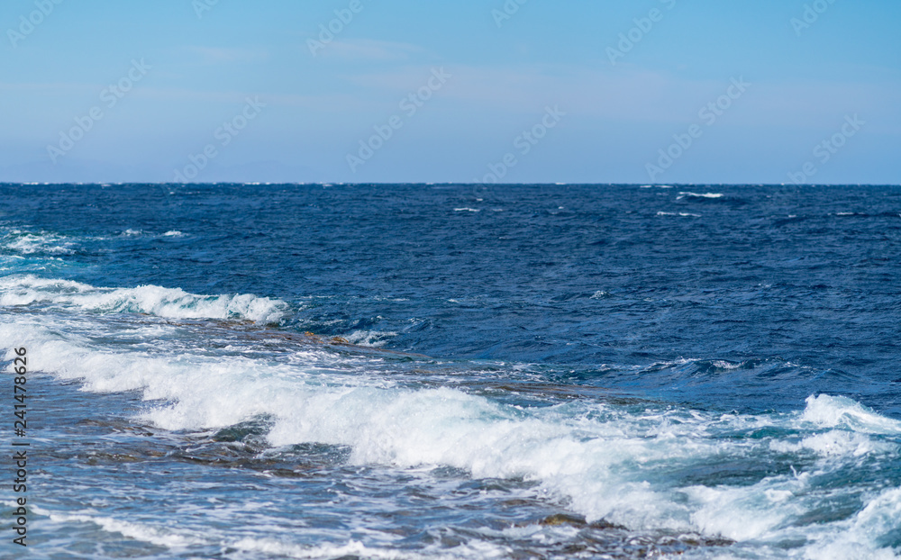 White waves breaking in a calm ocean