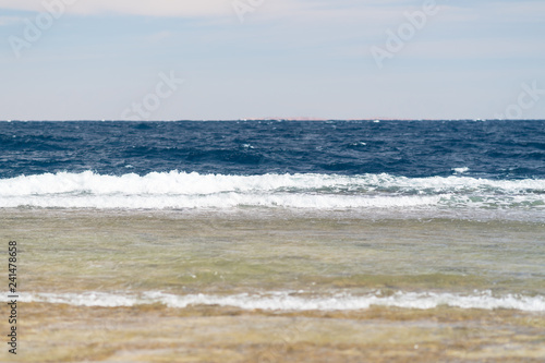 Waves breaking on a sandy beach in summer
