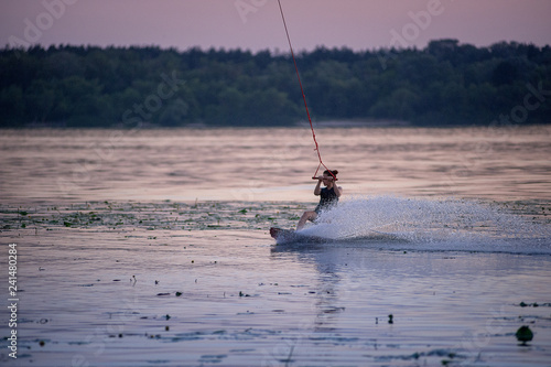 Girl riding on Wakeboarding on sunset. splashes of water