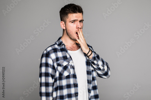 Young handsome man yawn isolated on gray background photo