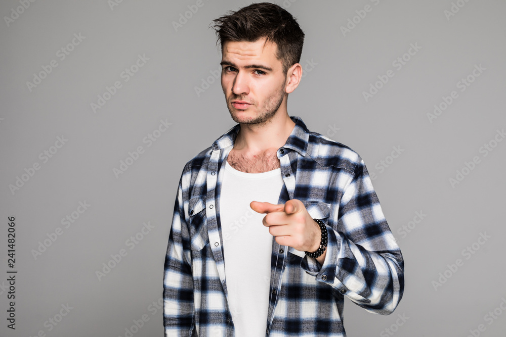 Choosing you. Confident young handsome man in plaid shirt pointing you and while standing against gray background Choosing you. Confident young handsome man in plaid shirt pointing you and while standing against gray background