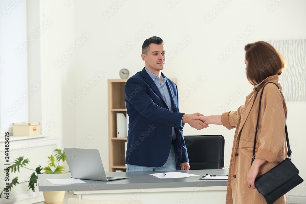 Human resources manager shaking hands with applicant after job interview in office Human resources manager shaking hands with applicant after job interview in office