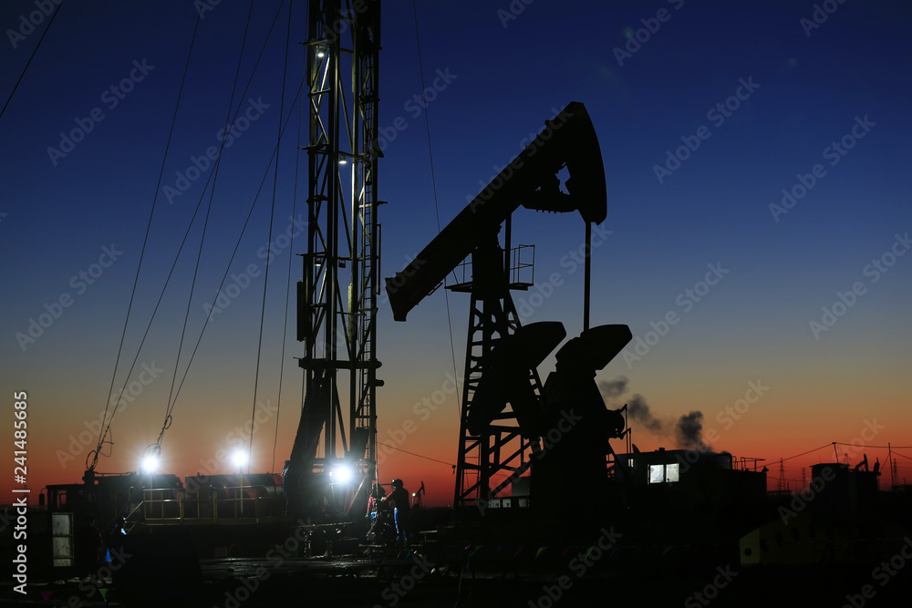 The pumping unit is at work in the evening of the oilfield The pumping unit is at work in the evening of the oilfield