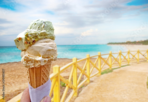 Hand is holding the vanilla ice cream.This is situated in tropical resort in Caribbean.