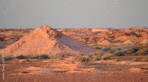 Large mounds of mine tailings in the outback Australian desert outside opal mining town of Coober Pedy at sunset photo