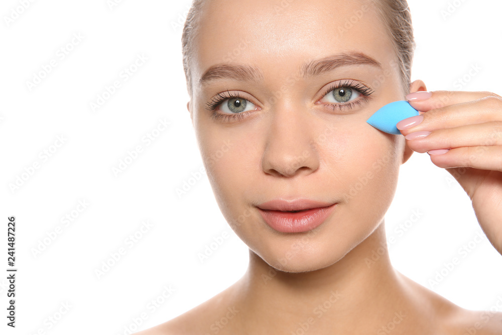 Young woman applying foundation on her face against white background Young woman applying foundation on her face against white background