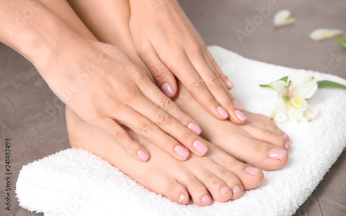 Woman touching her smooth feet and towel on grey background  closeup. Spa treatment