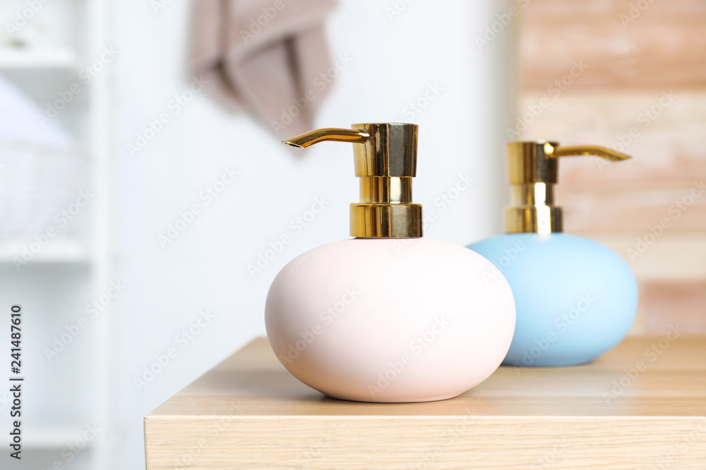 Obraz premium Stylish soap dispensers on table against blurred background. Space for text