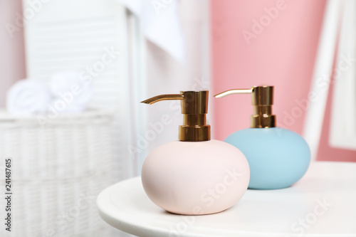 Stylish soap dispensers on table against blurred background. Space for text © New Africa