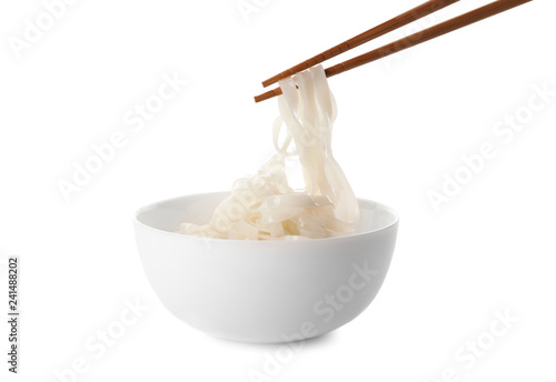 Taking rice noodles with chopsticks from bowl on white background photo