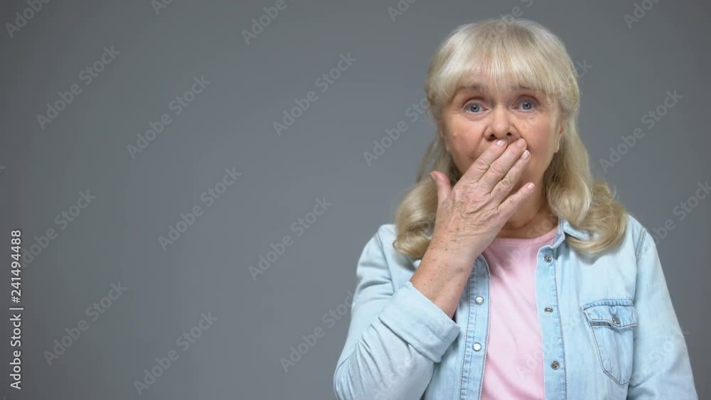 Shocked aging woman covering mouth with hand, astonished with news, emotions Shocked aging woman covering mouth with hand, astonished with news, emotions