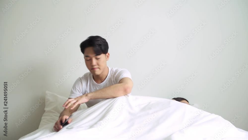 Young asian woman angry at her boyfriend for looking too much at his phone in bed. Social issues and social addiction concept.
