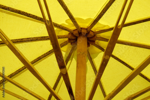 Back-lit yellow hand made bamboo umbrella.