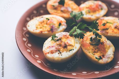 Fried hot boiled egg masala is a popular healthy breakfast or starter menu from India. With onion, coriander, black pepper, tomato and salt sprinkled over half of eggs