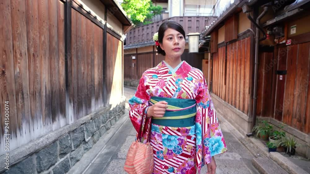 young lady with colorful flower pattern kimono dress walking in old street in ishibe alley. girl in japanese traditional costume walking in town with wooden style house surrounding stone road. young lady with colorful flower pattern kimono dress walking in old street in ishibe alley. girl in japanese traditional costume walking in town with wooden style house surrounding stone road.