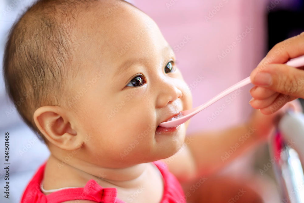 The baby is eating food with a blurred background. The baby is eating food with a blurred background.