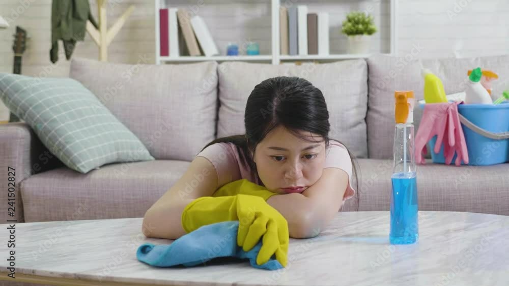 slow motion of upset woman unhappy using rag and detergent cleaning living room. unsatisfied young girl in protective gloves resting arms and head on table wiping. tired housewife housekeeping. slow motion of upset woman unhappy using rag and detergent cleaning living room. unsatisfied young girl in protective gloves resting arms and head on table wiping. tired housewife housekeeping.
