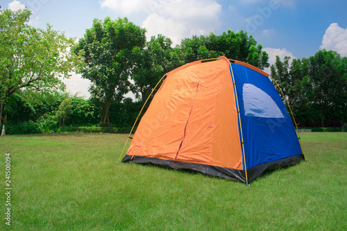 Orange and blue color family camping tent without rain fly setup on green park campsite.