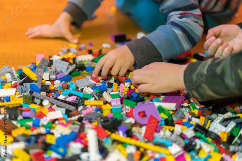 Close up of colorful plastic bricks on the floor. Early learning. Children s plastic constructor on the floor. Children s hands play a little constructor.