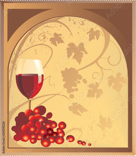 A glass with red wine and a bunch of grapes on a light brown background.