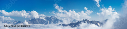 Panoramic of Caucasus mountains peaks in the snow and clouds