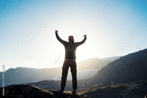 Happy sucsessfull man raises hands in the mountains