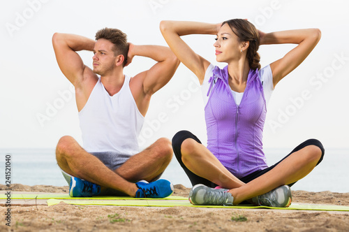 Couple training yoga on beach