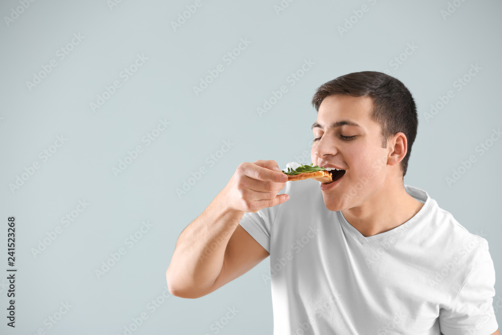 Young man eating tasty pizza on light background Young man eating tasty pizza on light background