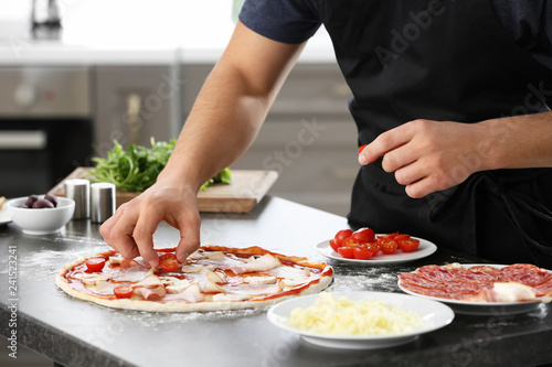 Fototapeta Naklejka Na Ścianę i Meble -  Young man preparing tasty pizza at table