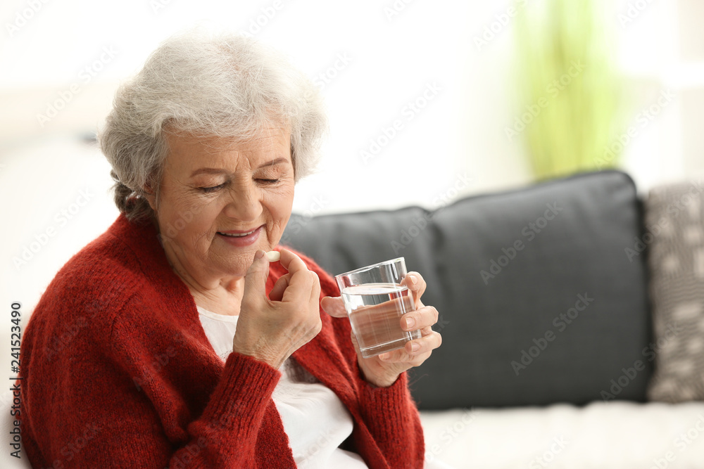 Elderly woman taking pill at home Elderly woman taking pill at home