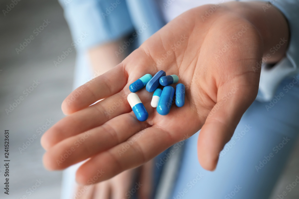 Young woman holding different pills, closeup