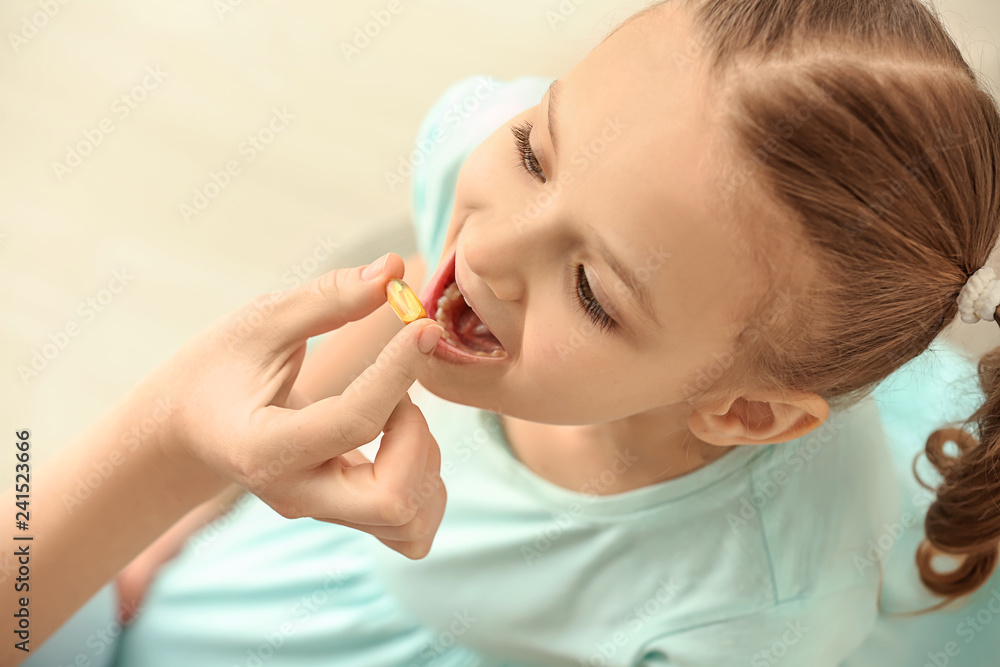 Young mother giving pill to her daughter, indoors Young mother giving pill to her daughter, indoors