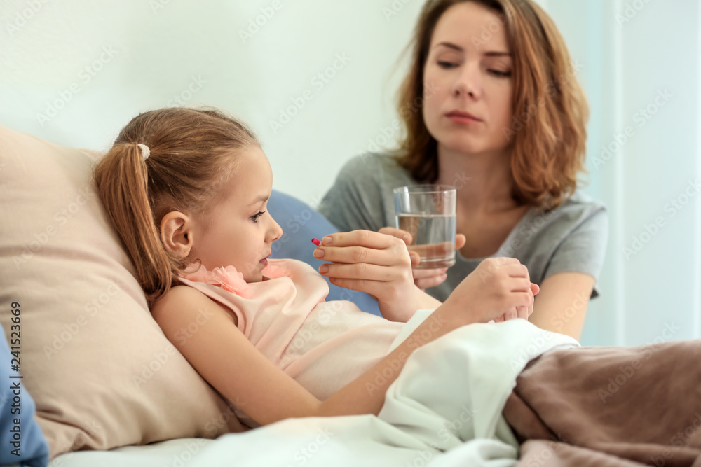 Young woman giving pill for her ill daughter in bed Young woman giving pill for her ill daughter in bed