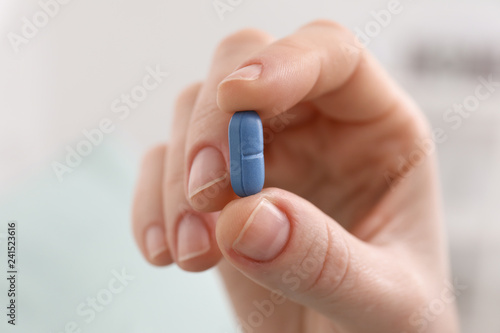 Young woman holding pill, closeup