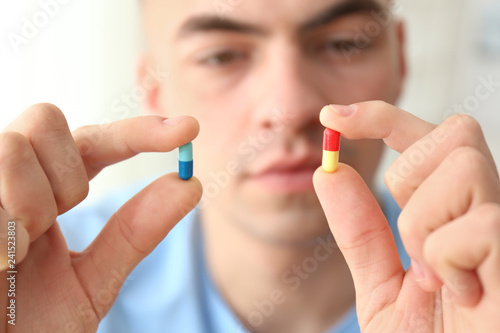 Young man holding different pills  closeup