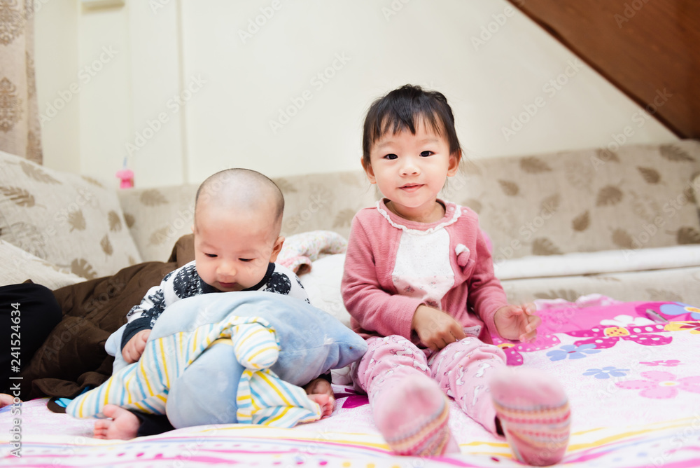Closeup of happy little child playing over the bed in a relaxed morning with her little baby sister. Closeup of happy little child playing over the bed in a relaxed morning with her little baby sister.