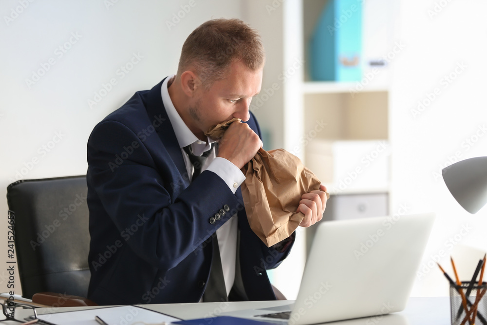 Fototapeta premium Man having panic attack at workplace in office