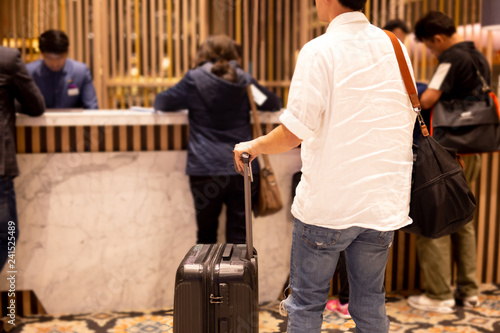 Man holding passport with suitcase waiting to checking in at hotel.