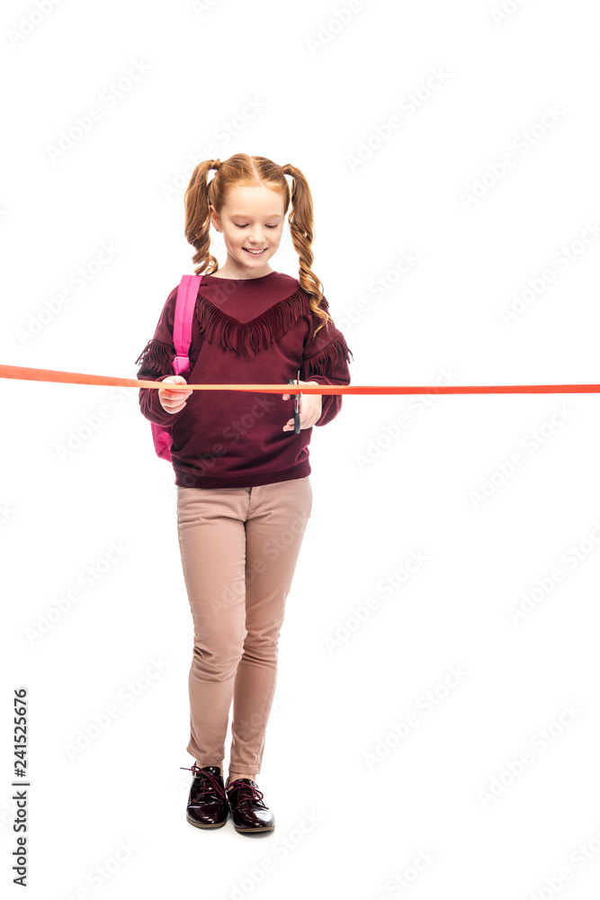 smiling schoolgirl cutting red ribbon isolated on white smiling schoolgirl cutting red ribbon isolated on white
